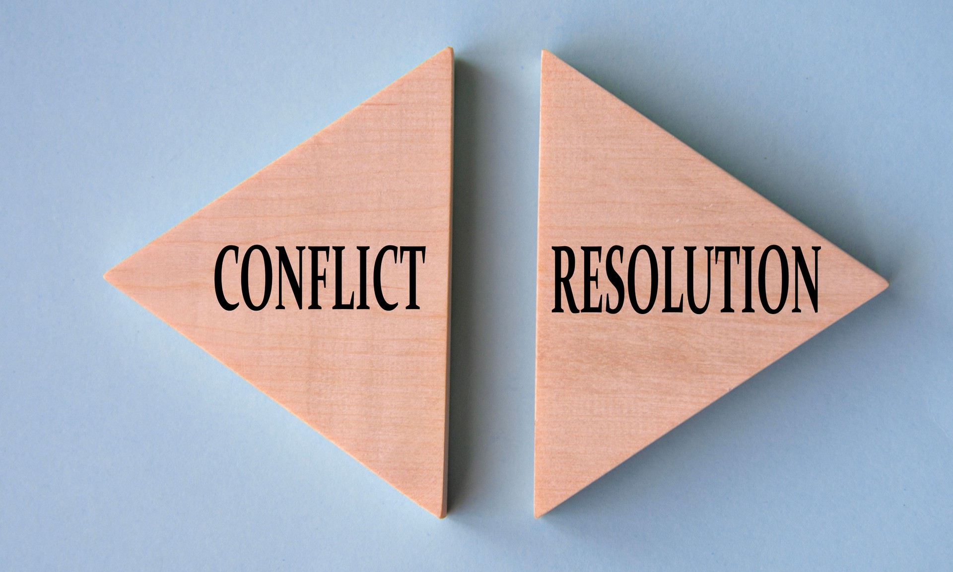CONFLICT and RESOLUTION - words on wooden triangles on grey-blue background